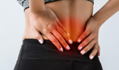 panoramic shot of sportswoman with lower back pain isolated on g