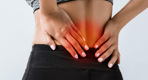 panoramic shot of sportswoman with lower back pain isolated on g